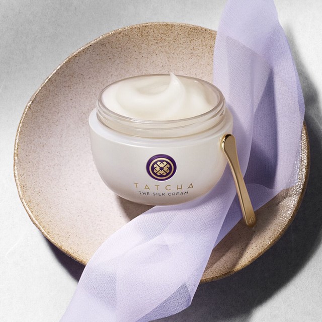 The Silk Cream, without a cap, on top of silk and a bowl.