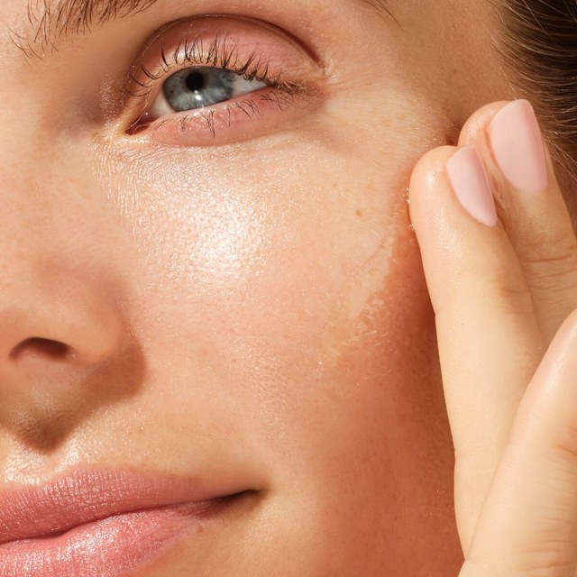 Shot of model applying The Brightening Serum onto face.