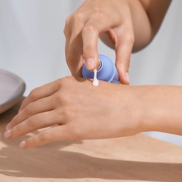 Model applying The Dewy Serum on hand.